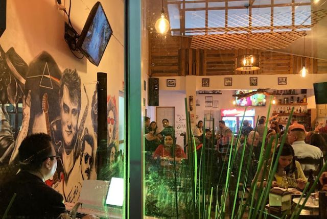 Imagen del animado ambiente en nuestro restaurante, donde clientes disfrutan de la velada en un ambiente acogedor. Algunos conversan animadamente en mesas decoradas con velas y flores, mientras otros saborean nuestros deliciosos platillos. La atmósfera es cálida y alegre, con luces suaves y una decoración elegante que crea un ambiente perfecto para una experiencia gastronómica memorable